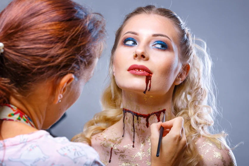 Wizażystka poprawiająca makijaż cosplayowy z użyciem sztucznej krwi